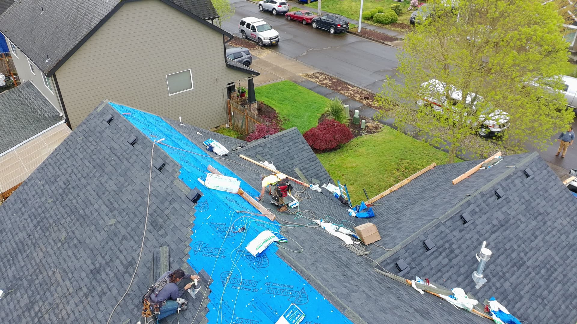 Abiqua Roofing crew laying synthetic underlayment and new shingles across a residential roof